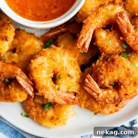 Crispy coconut shrimp on a plate with dipping sauce.