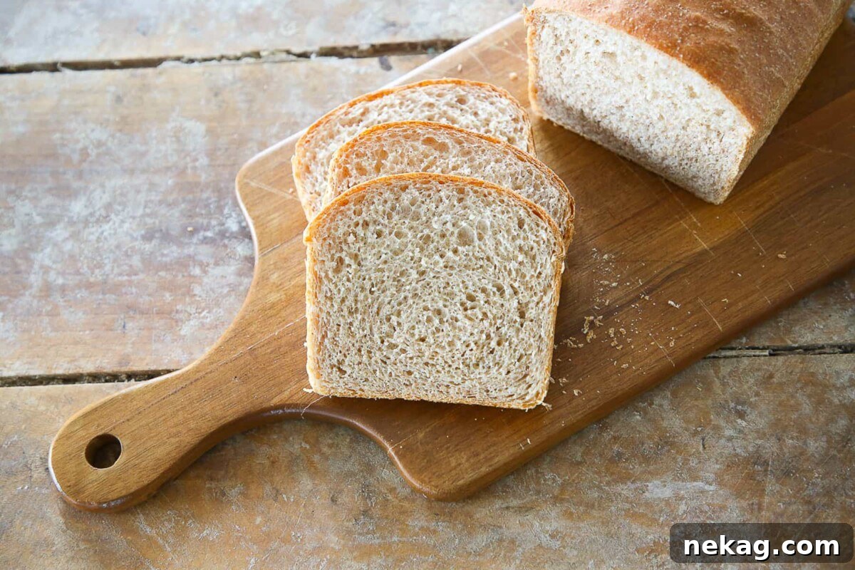 Hearty Whole Wheat Sandwich Loaf 3 A fresh, homemade whole wheat sandwich loaf perfectly sliced on a rustic wooden cutting board, showcasing its even texture and golden brown crust.