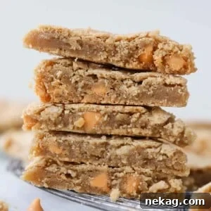 Stack of chewy blondies, showing their golden brown exterior and rich, dense texture from a side view.