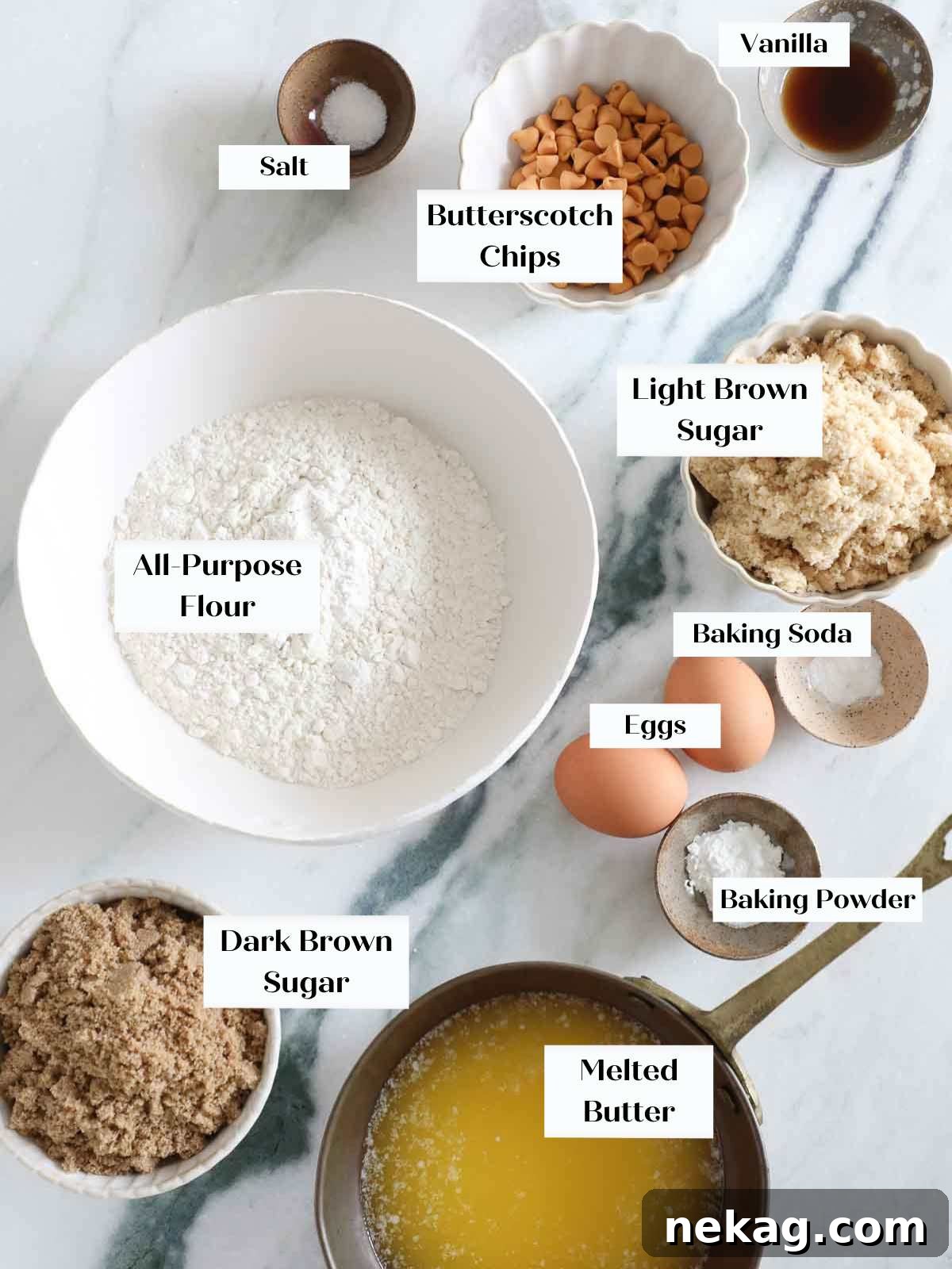 Neatly arranged blondies ingredients on a light marble countertop, including flour, sugars, butter, eggs, and vanilla.
