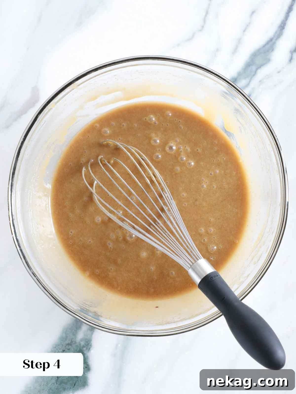 A large mixing bowl filled with whisked wet ingredients for blondies, showing a smooth, glossy, amber-colored mixture.