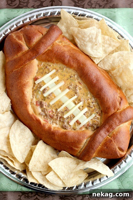 Close-up of the football dip bowl, showing the intricate bread shape and the rich queso dip inside.