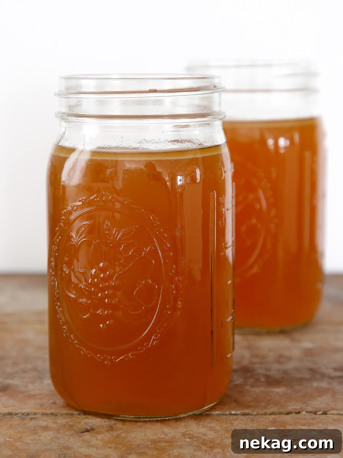 Crafting Perfect Chicken Broth from Scratch 2 Two mason jars filled with golden homemade chicken broth, ready for use or storage.