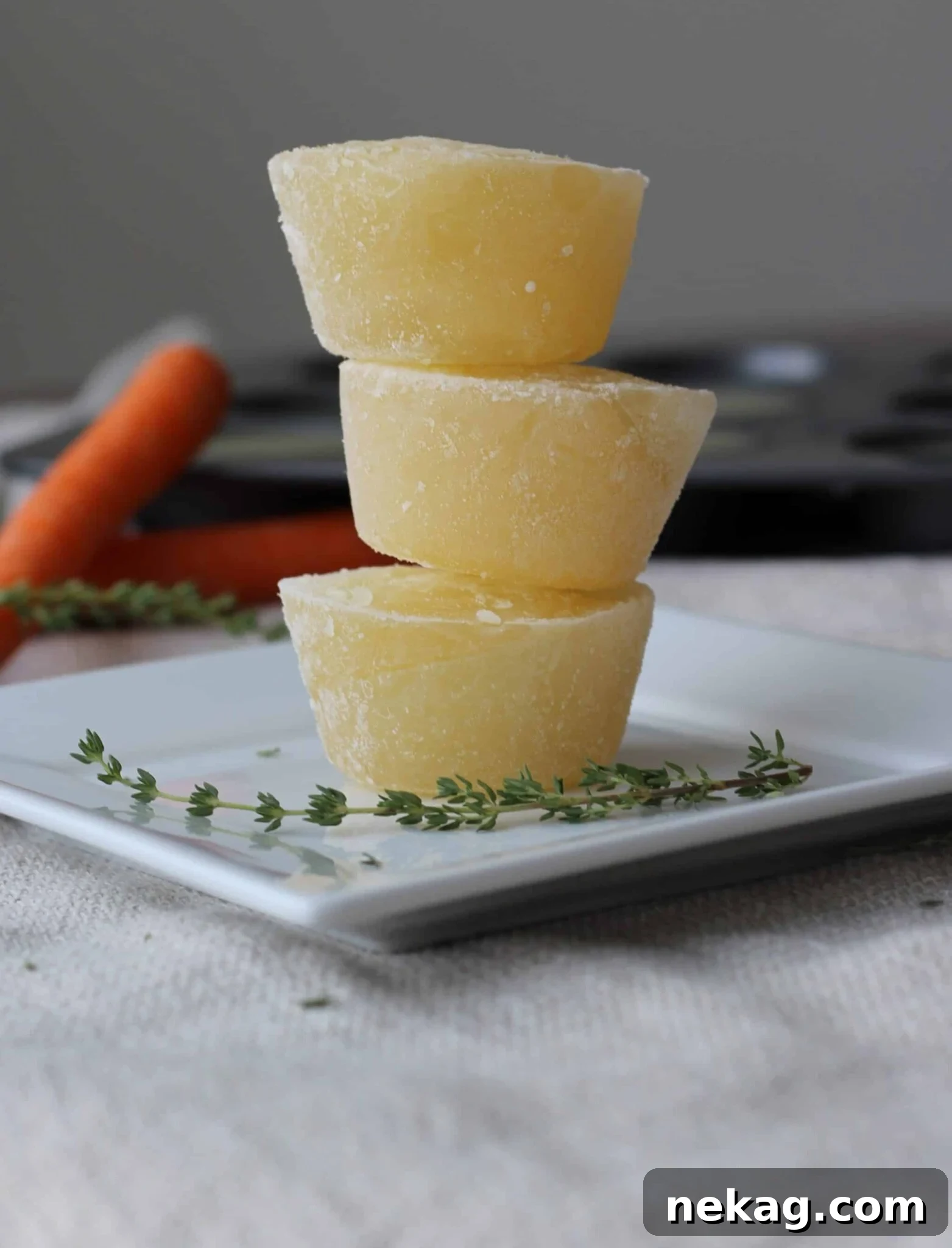 Crafting Perfect Chicken Broth from Scratch 4 Homemade chicken broth frozen into individual, muffin-cup-sized portions, neatly stacked.