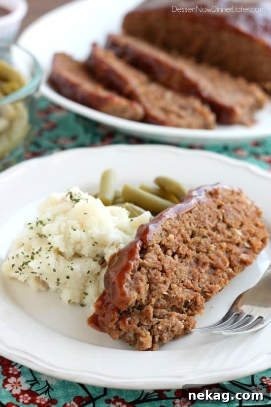 Close-up of a slice of slow cooker meatloaf, showing its moist texture and the rich glaze.