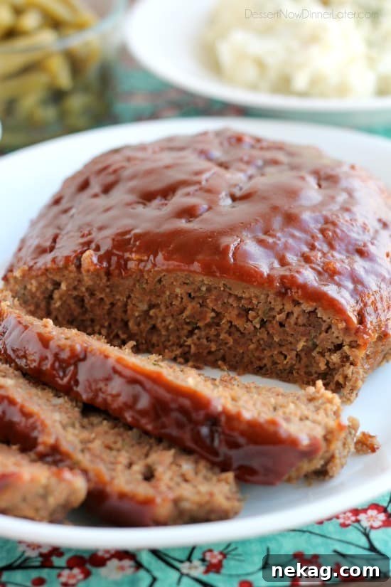 A serving of slow cooker meatloaf with a side of mashed potatoes and green beans, showcasing a complete meal.