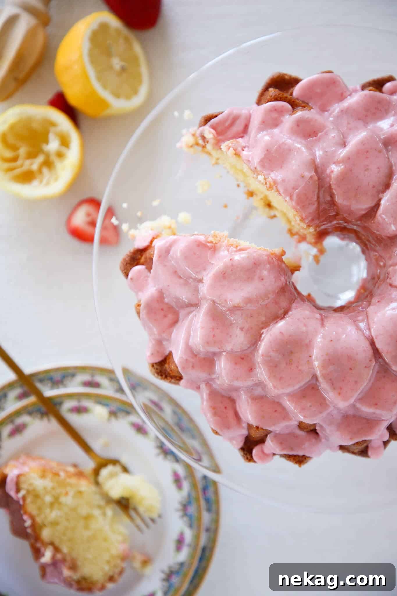 Zesty Lemon Loaf 2 Lemon Pound Cake Strawberry Icing sliced cake on glass pedestal white background Valentine's Day Desserts.