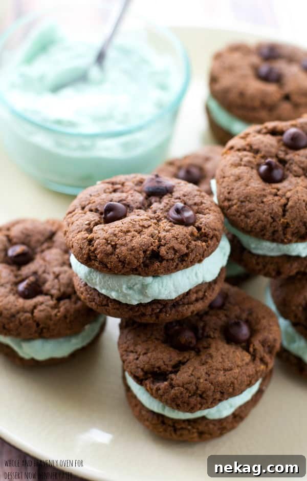 A close-up of a chocolate mint cream cookie sandwich, highlighting the thick layer of mint coconut cream between two dark chocolate cookies.