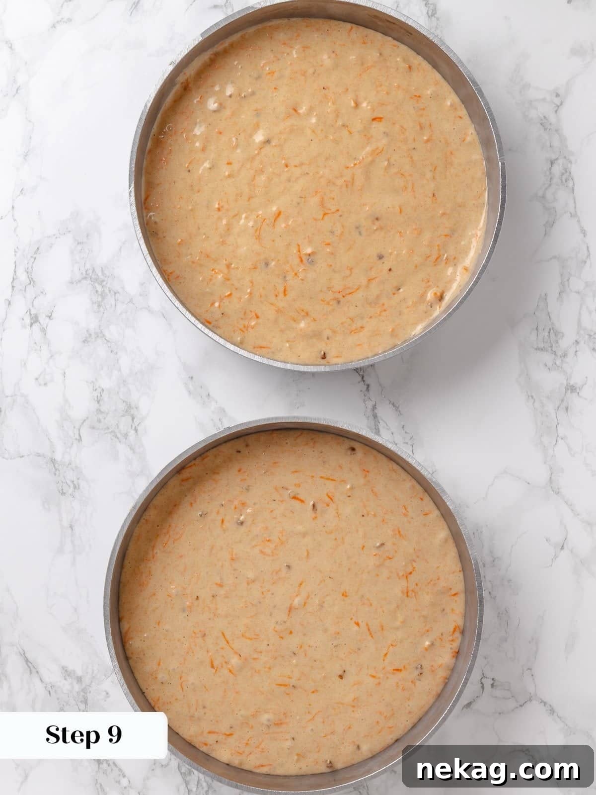 Carrot cake batter being evenly divided into two round cake pans.