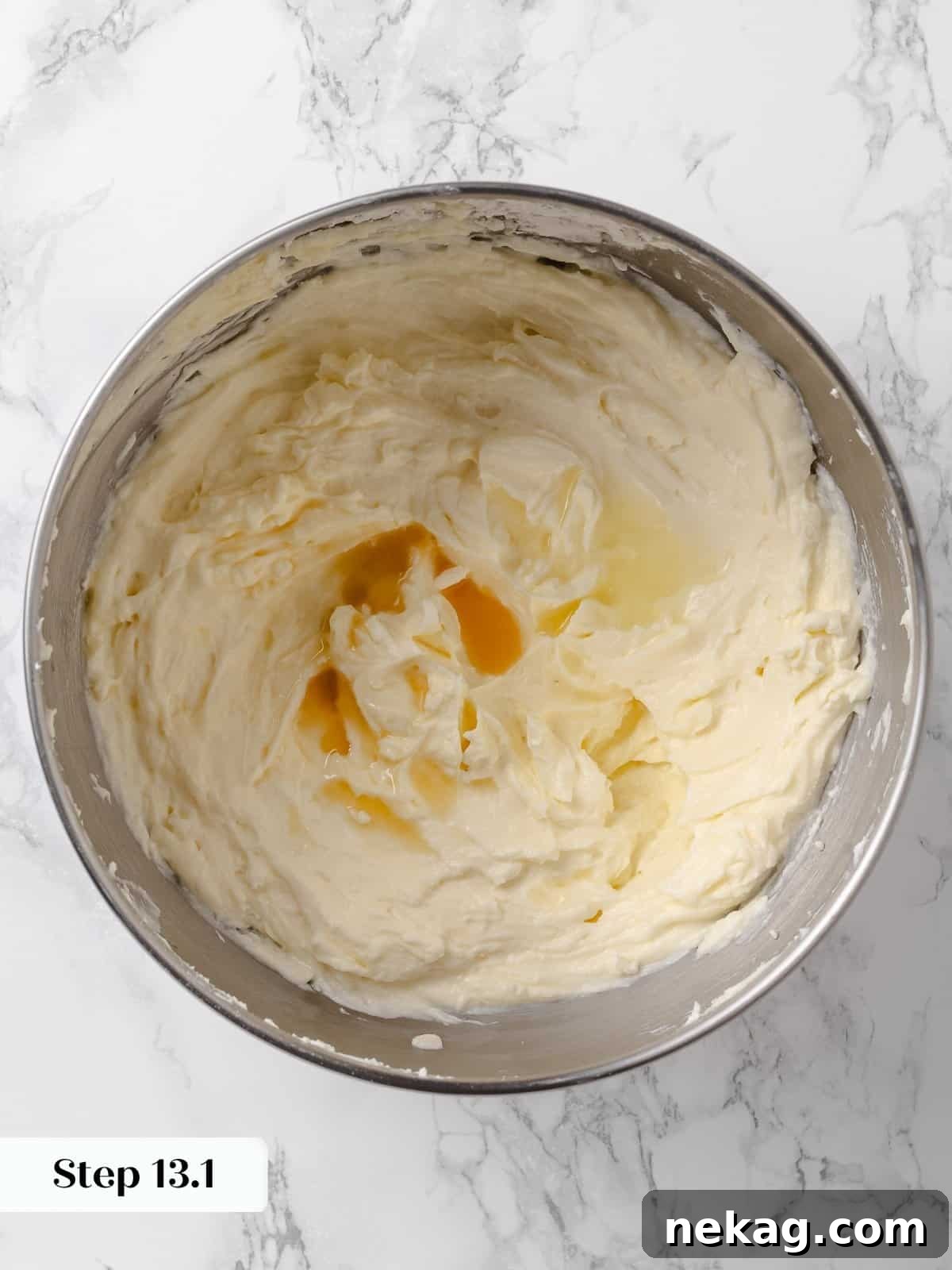 Vanilla extract being poured into the cream cheese frosting.