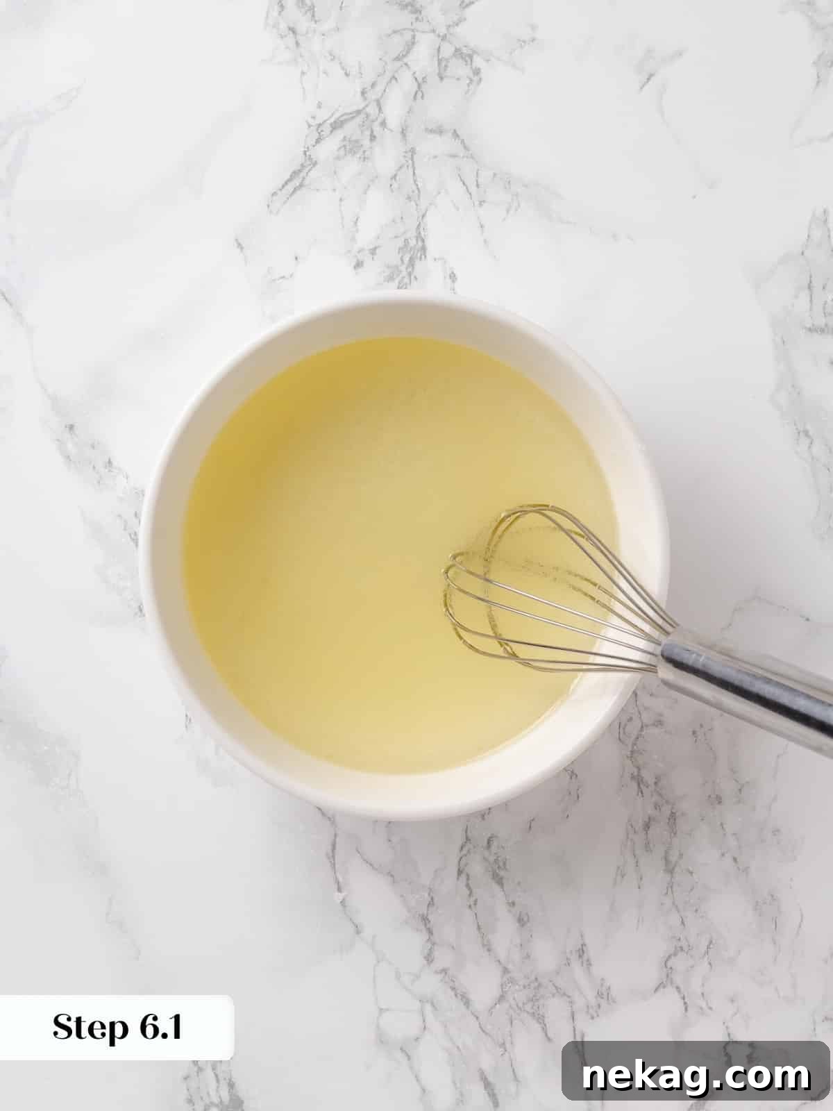 Glass containing vegetable oil and lemon juice, whisked together.