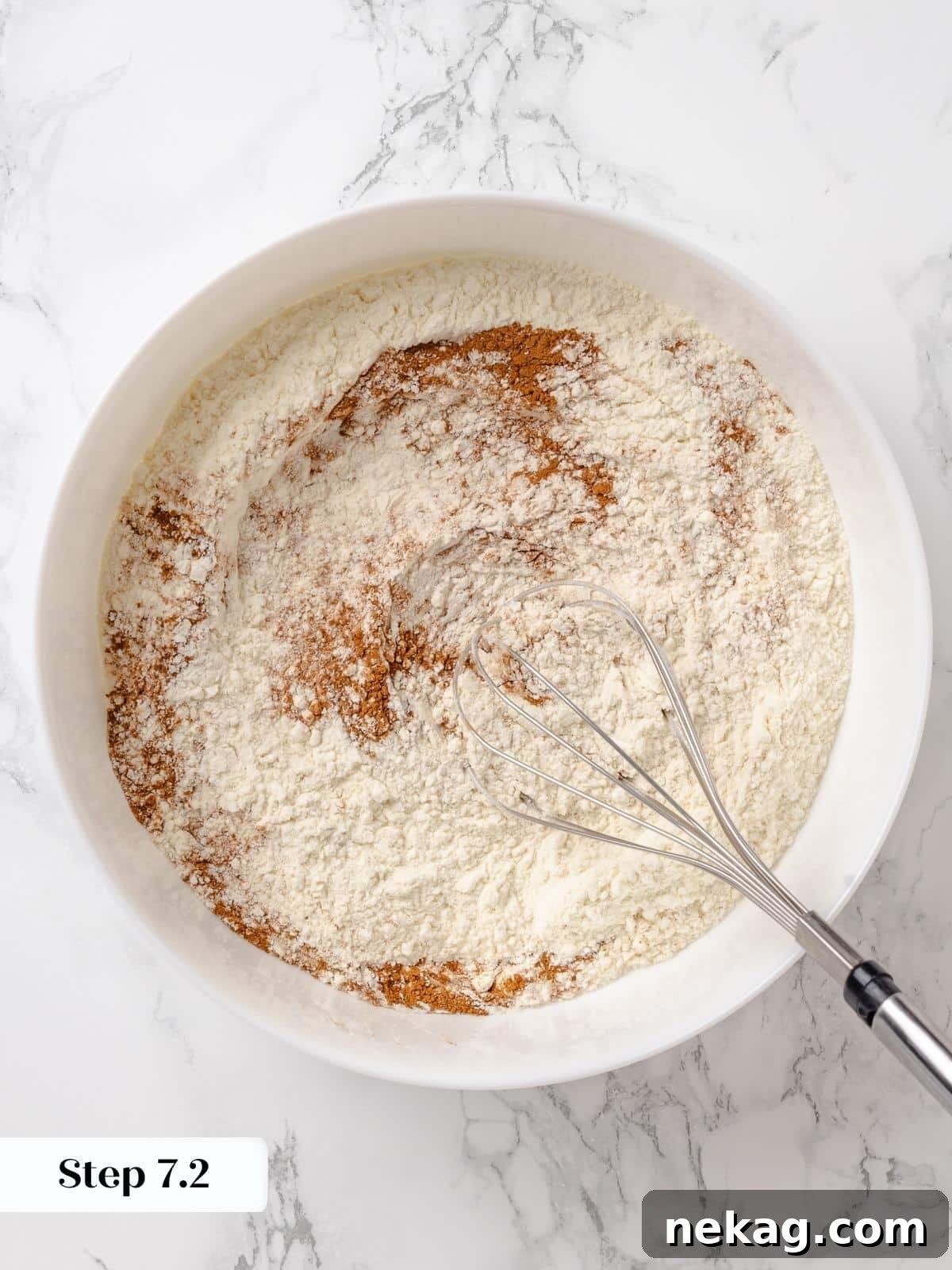 Rubber spatula gently mixing dry ingredients into the whipped batter.