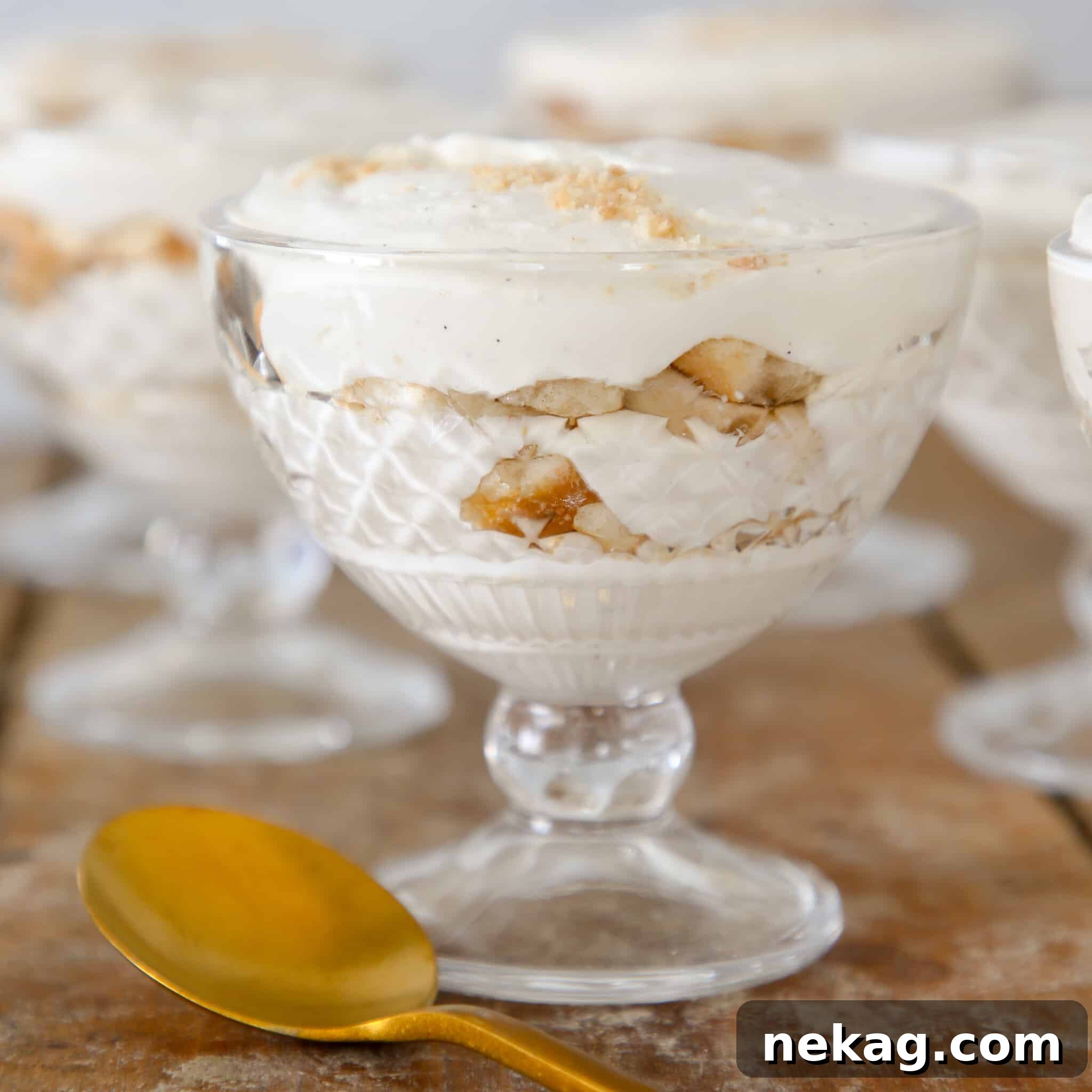 A beautifully presented individual serving of homemade banana pudding in a clear coupe glass, showcasing its distinct layers.