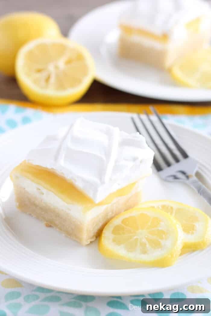 A square slice of Lemon Curd Dessert on a white plate, showcasing its four delicious layers: shortbread crust, cream cheese, golden lemon curd, and whipped cream.