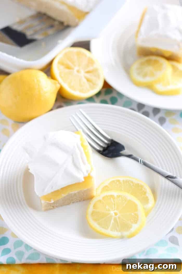 Close-up of a Lemon Curd Dessert bar, showing the smooth, vibrant yellow lemon curd layer contrasting with the white whipped cream and golden crust.