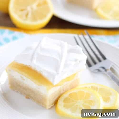 Lemon curd dessert square on plate made with a shortbread crust, sweetened cream cheese, lemon curd, and whipped cream.