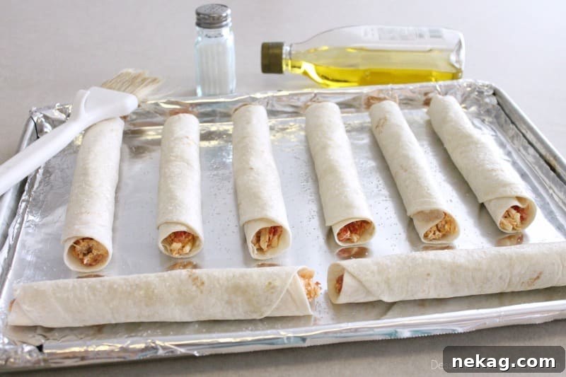 Crispy Zesty Chicken Taquitos 8 Baked Zesty Chicken Taquitos, golden brown and crispy, cooling on a baking sheet after coming out of the oven.