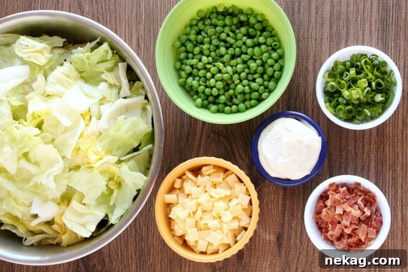 Sarah's Salad A Lion House Specialty 3 An overhead view of Sarah's Salad ingredients laid out, showcasing the vibrant colors of iceberg lettuce, green peas, crispy bacon, and Swiss cheese, emphasizing the freshness before mixing.