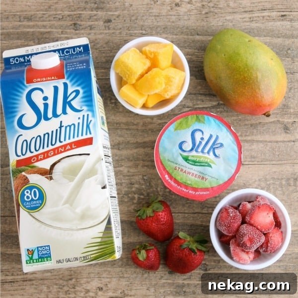 Creamy Dairy-Free Strawberry Mango Delight 3 Ingredients laid out for a Strawberry Mango Smoothie: Silk Coconut Milk, Silk Dairy-Free Strawberry Yogurt, frozen strawberries, and frozen mango chunks.