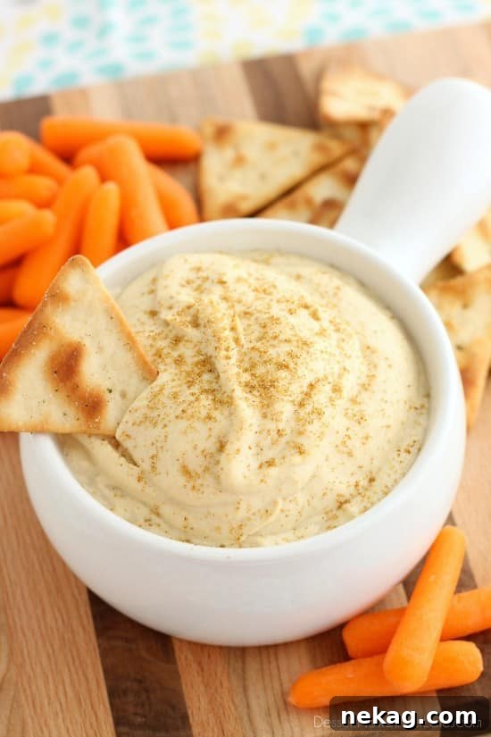 Whip Up Garlicky Hummus 2 A beautifully smooth and creamy bowl of Easy Garlic Hummus, garnished with a drizzle of olive oil and a sprinkle of paprika, ready to be served with fresh vegetables and pita bread for a healthy snack.