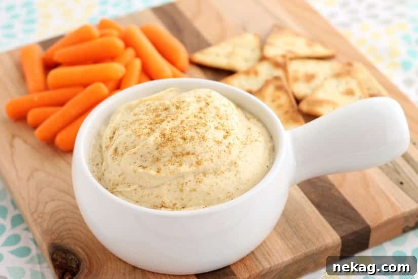 Whip Up Garlicky Hummus 6 A top-down view of a vibrant spread featuring a bowl of Easy Garlic Hummus, surrounded by an assortment of colorful crackers and fresh vegetables, inviting guests to enjoy.
