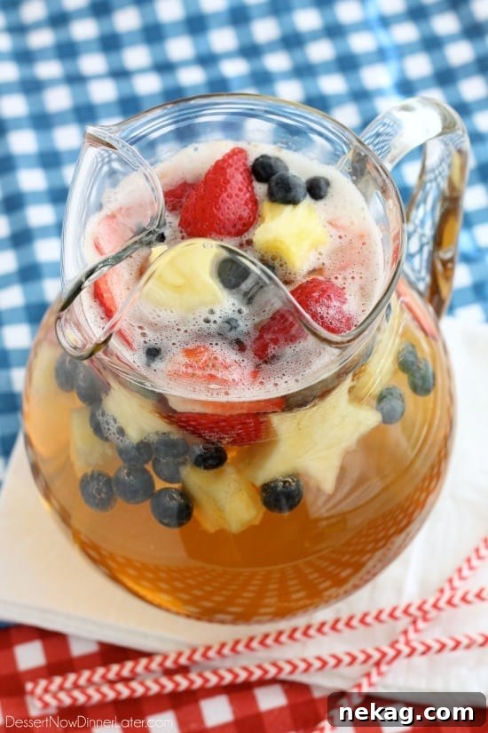 Patriotic Spark 4 Patriotic Punch ready for serving in a large pitcher, showcasing layers of fruit and sparkling liquid