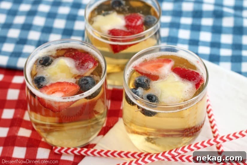 Patriotic Spark 6 Ingredients for Patriotic Punch: bottles of white grape juice and ginger ale, alongside fresh strawberries, blueberries, and pineapple stars