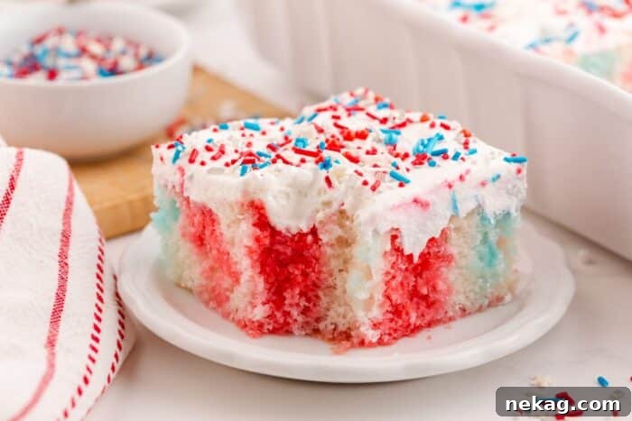 A slice of 4th of July poke cake on a plate with a forkful taken out.