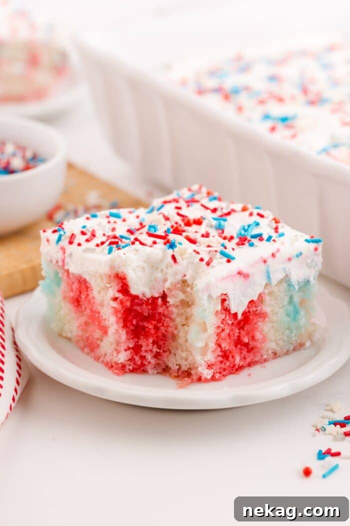 A slice of 4th of July poke cake on a plate with a forkful taken out.