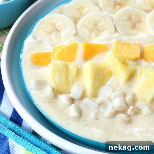 A vibrant tropical smoothie bowl, garnished with fresh fruit, nuts, and seeds.
