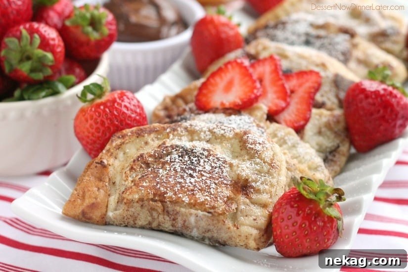 A stack of golden-brown Stuffed French Toast slices, drizzled with syrup and adorned with fresh berries, ready to be served.