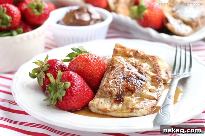 A close-up of a fork cutting into a piece of Stuffed French Toast, revealing the melted Nutella and juicy strawberries inside.