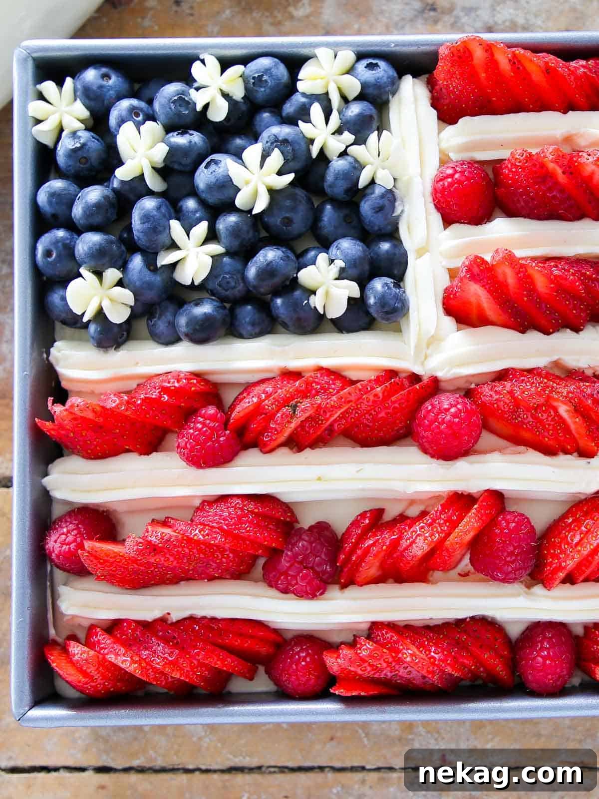 american flag cake with berries unsliced, ready to be served at a July 4th celebration.