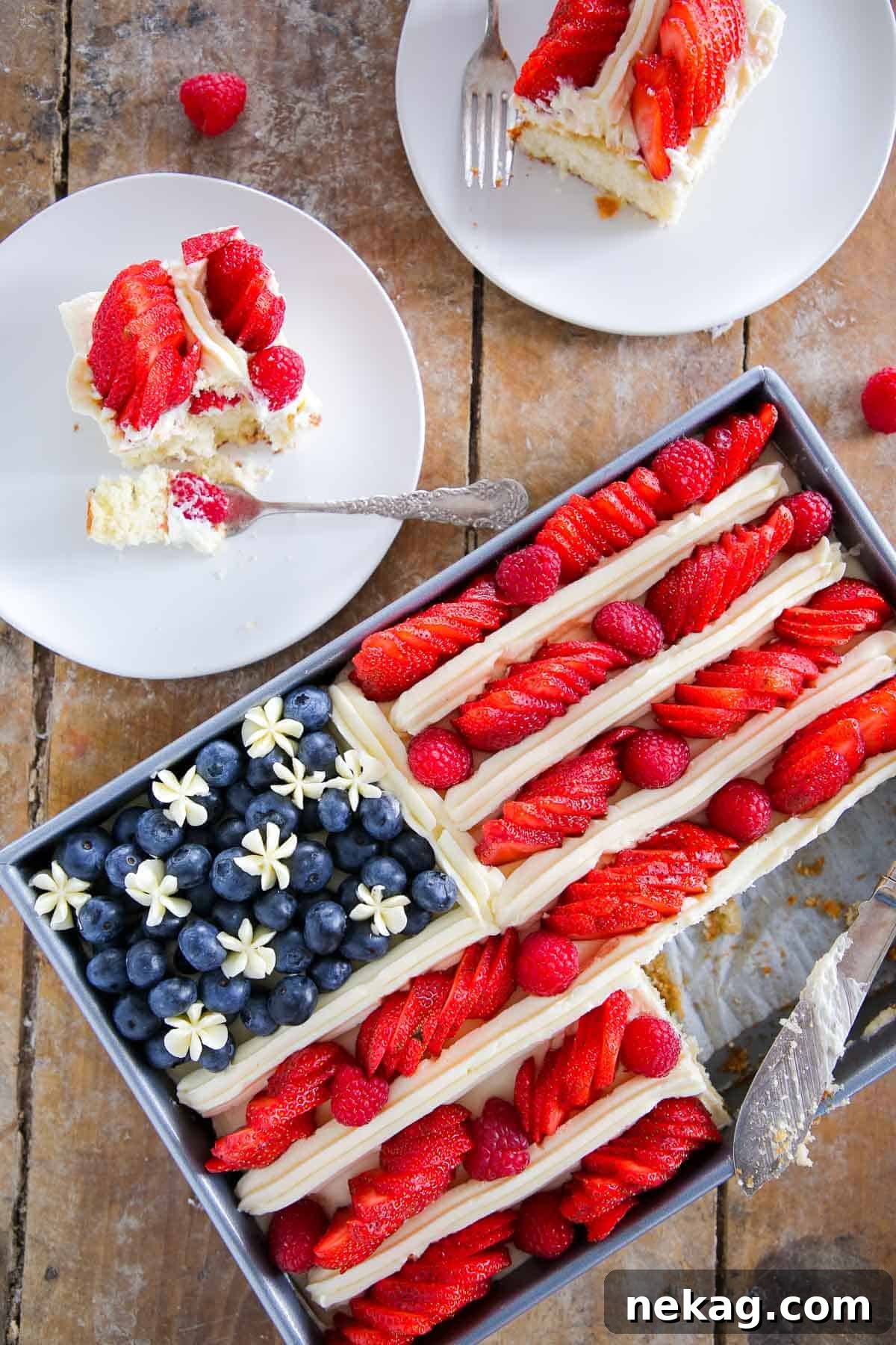 american flag cake with berries with cake slices on white plates, showcasing a perfectly portioned dessert.