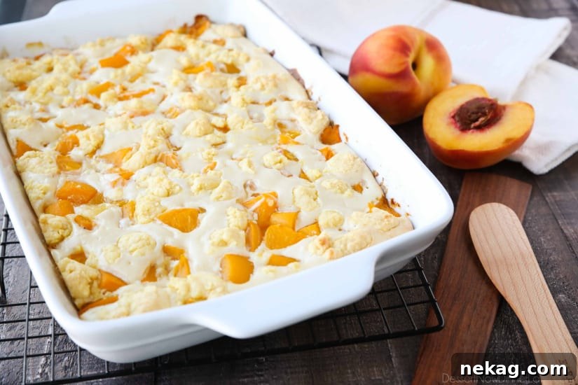 A slice of Peaches and Cream Cobbler showcasing its distinct layers: a bottom cake crust, juicy peaches, creamy cheesecake, and a crumbly cake topping.
