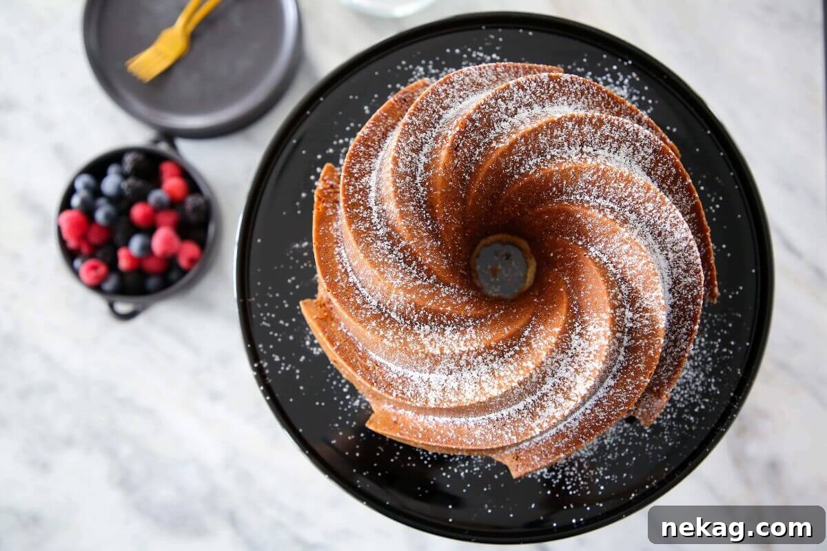 Velvet Sour Cream Pound Cake 3 A slice of Sour Cream Pound Cake garnished with a colorful bowl of fresh berries, highlighting its versatility as a dessert.