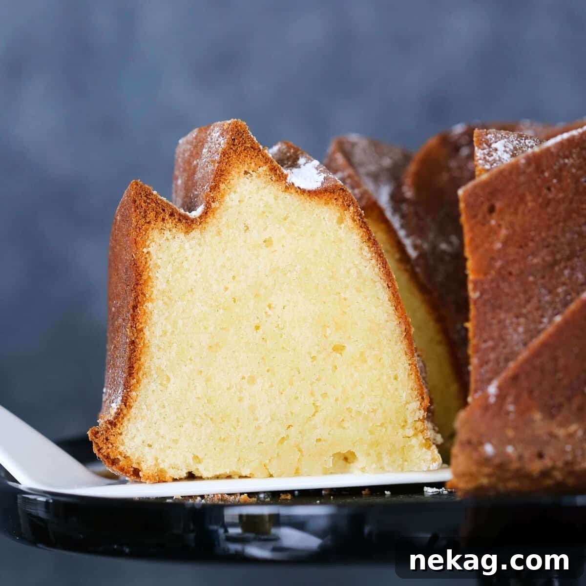 Velvet Sour Cream Pound Cake 4 A beautiful Sour Cream Pound Cake presented on a rustic cake server, highlighting its impressive form.