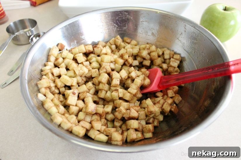 Decadent Chocolate Caramel Apple Crumble Squares 6 Diced apples mixed with brown sugar, cornstarch, cinnamon, and lemon juice in a bowl.