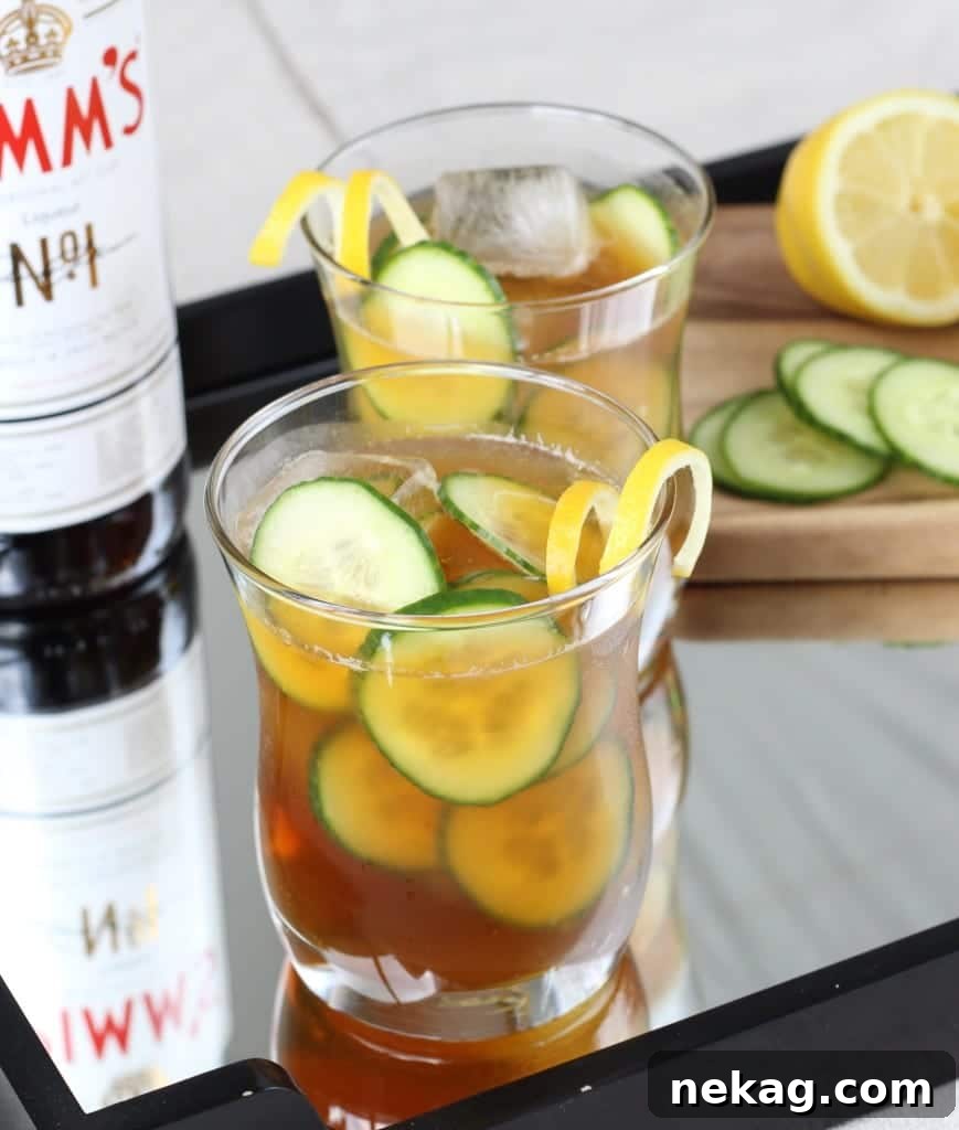 A refreshing Pimm's Cup with cucumber slices and a lemon garnish in a clear glass.