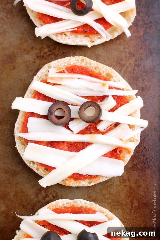 Spooky Swaddle Pizzettes 5 A child's hands carefully placing string cheese strips on an English muffin base.