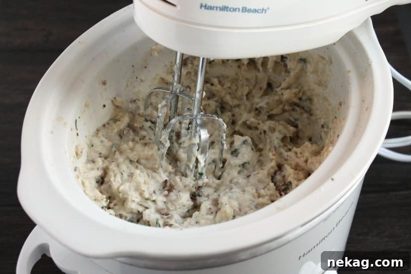 Mashing slow cooker potatoes with a hand mixer.