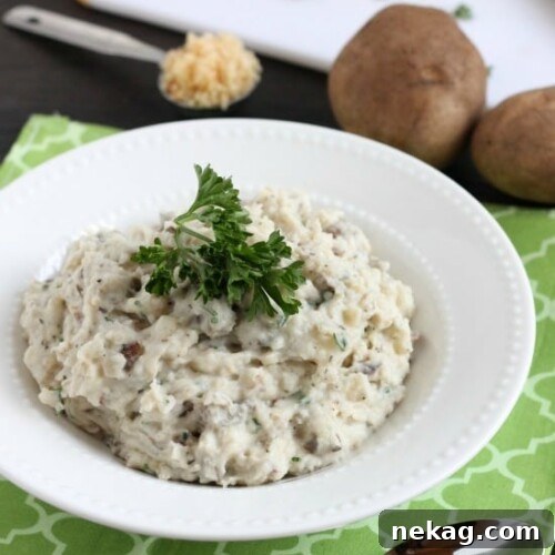 Close-up of a bowl of homemade Slow Cooker Mashed Potatoes, garnished with fresh herbs.
