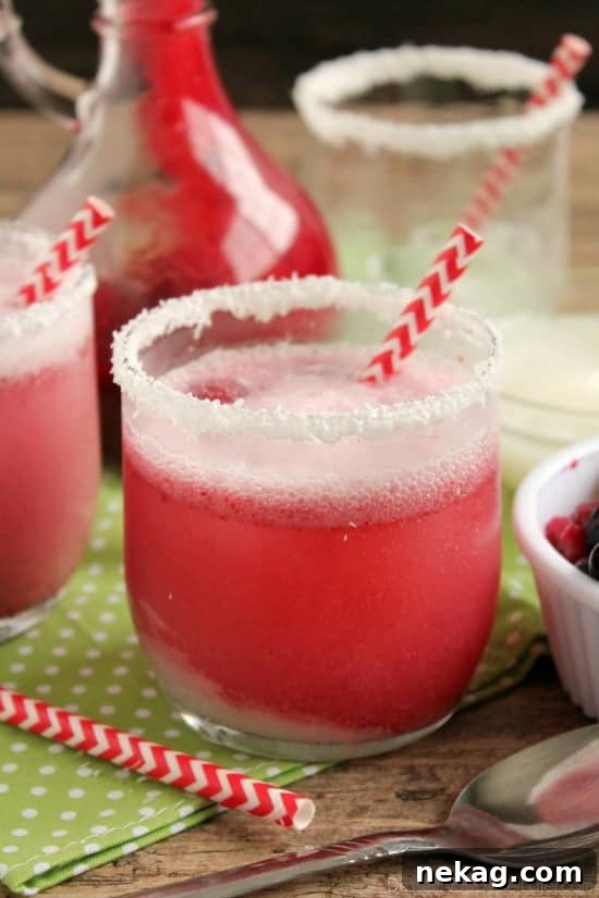 A festive glass of Berry Coconut Spritzer, garnished with fresh berries and a coconut-flaked rim, ready for holiday celebrations.