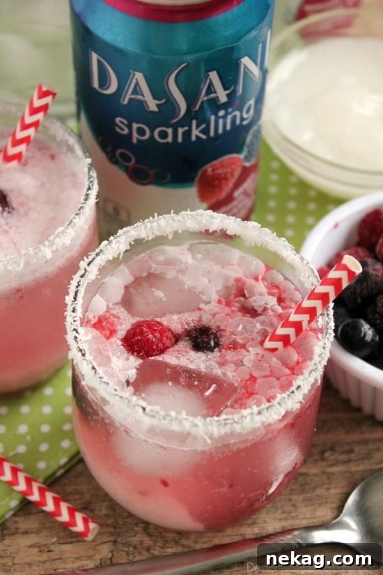 A hand carefully dipping a glass rim into unsweetened coconut flakes for a decorative finish on the Berry Coconut Spritzer.