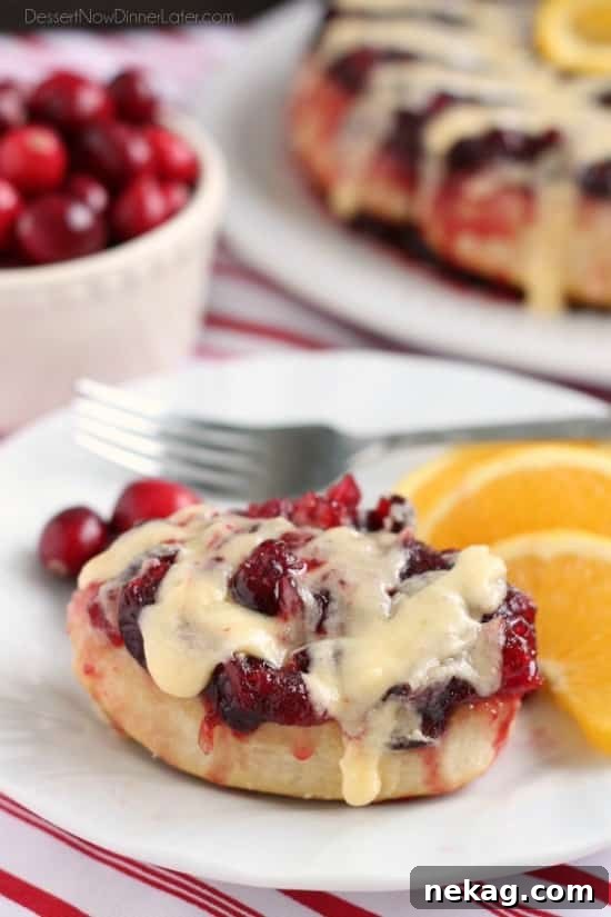 Zesty Cranberry Orange Upside-Down Buns 2 Beautifully baked upside-down cranberry orange rolls on a serving platter, drizzled with orange cream cheese glaze, ready for a festive Christmas breakfast.
