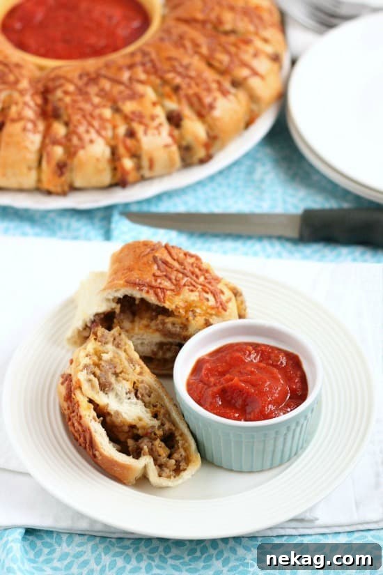 Hearty Sausage Stromboli 5 Baked Sausage Stromboli sliced and showing the cheesy, sausage-filled interior, ready for dipping.