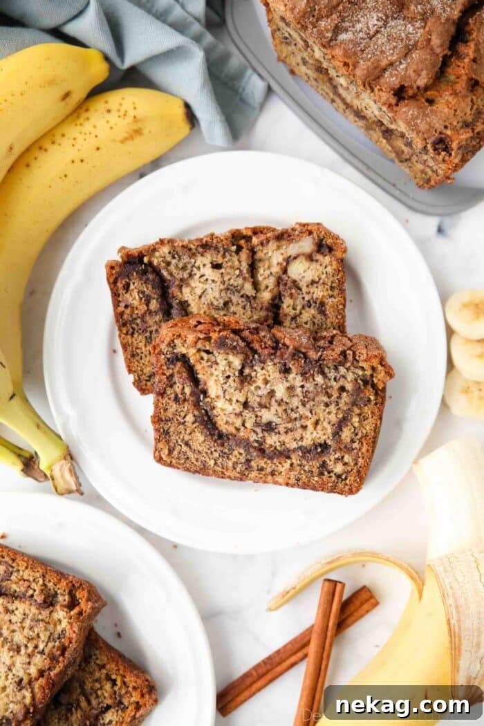 Two generous slices of moist cinnamon swirl banana bread, showcasing the golden-brown crust and inviting cinnamon ribbon within, presented on a white plate ready to be enjoyed.