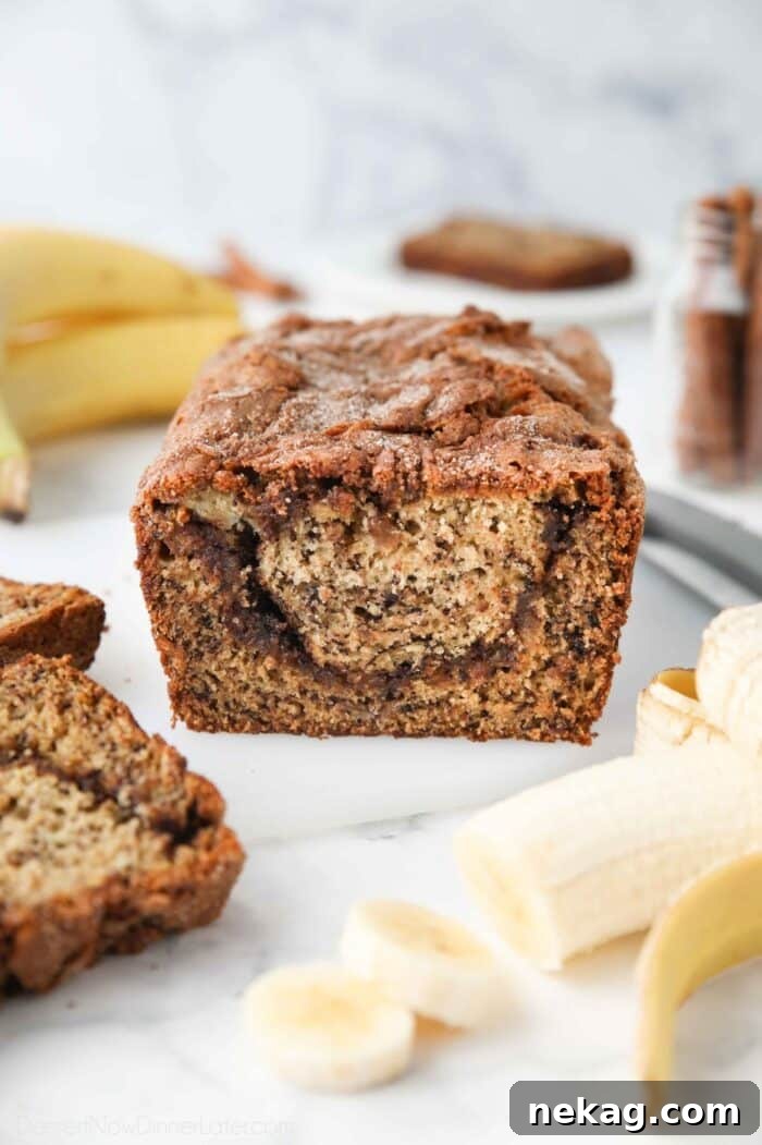 A close-up view of a slice of cinnamon swirl banana bread, highlighting the distinct, gooey cinnamon-sugar layer perfectly swirled through the moist banana bread crumb.