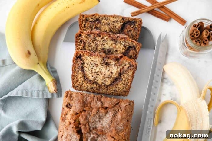 A freshly baked loaf of cinnamon swirl banana bread cooling on a wire rack, with several slices already cut, ready to be served.