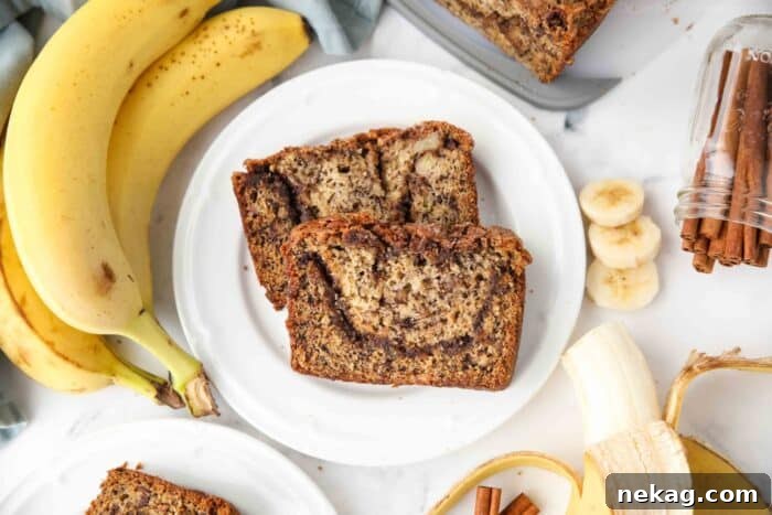 Two enticing slices of cinnamon swirl banana bread resting on a white plate, highlighting the perfectly baked crumb and visible cinnamon layers, ready for enjoyment.